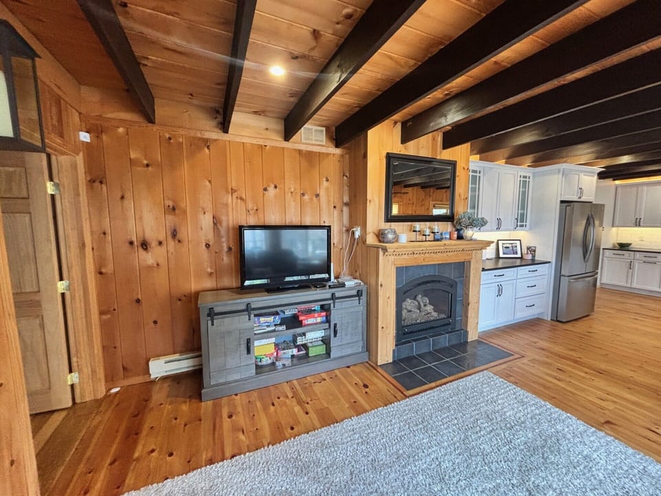 Gather in this warm, inviting space where rustic exposed beams meet modern comfort. Enjoy cozy evenings by the fireplace with entertainment close at hand in your fully-equipped cabin retreat.