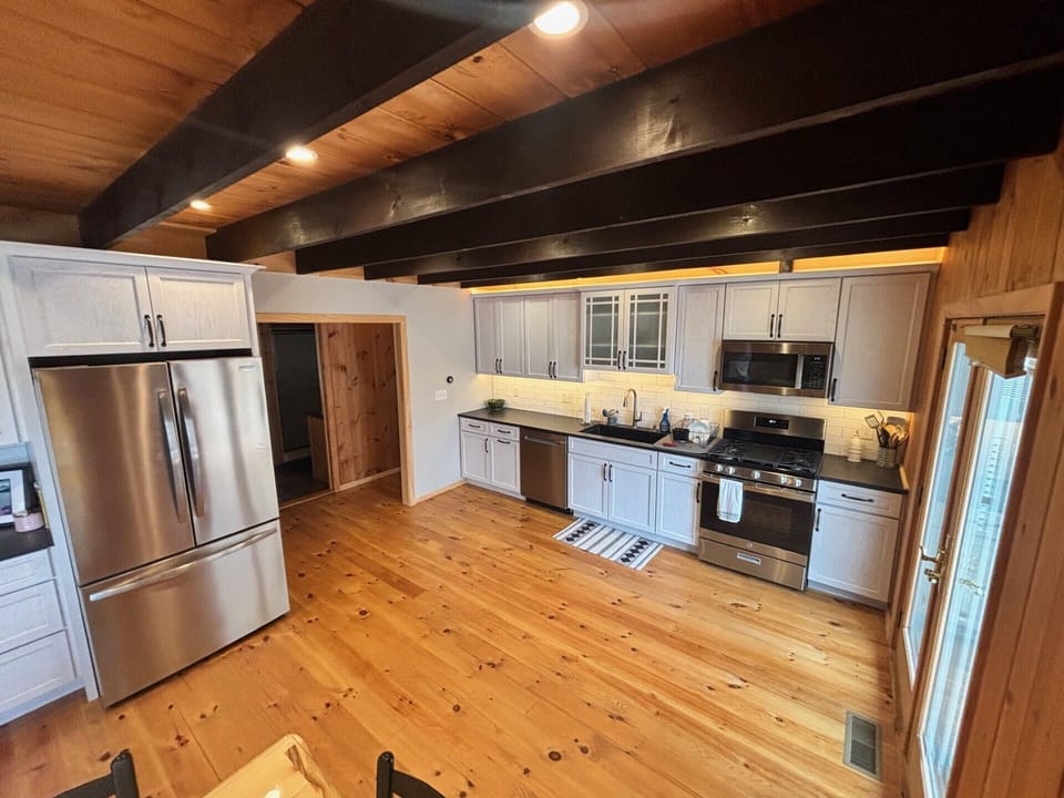 Picture yourself preparing meals in this spacious kitchen, where rustic wood beams and soft lighting create a warm, inviting atmosphere for your culinary adventures.