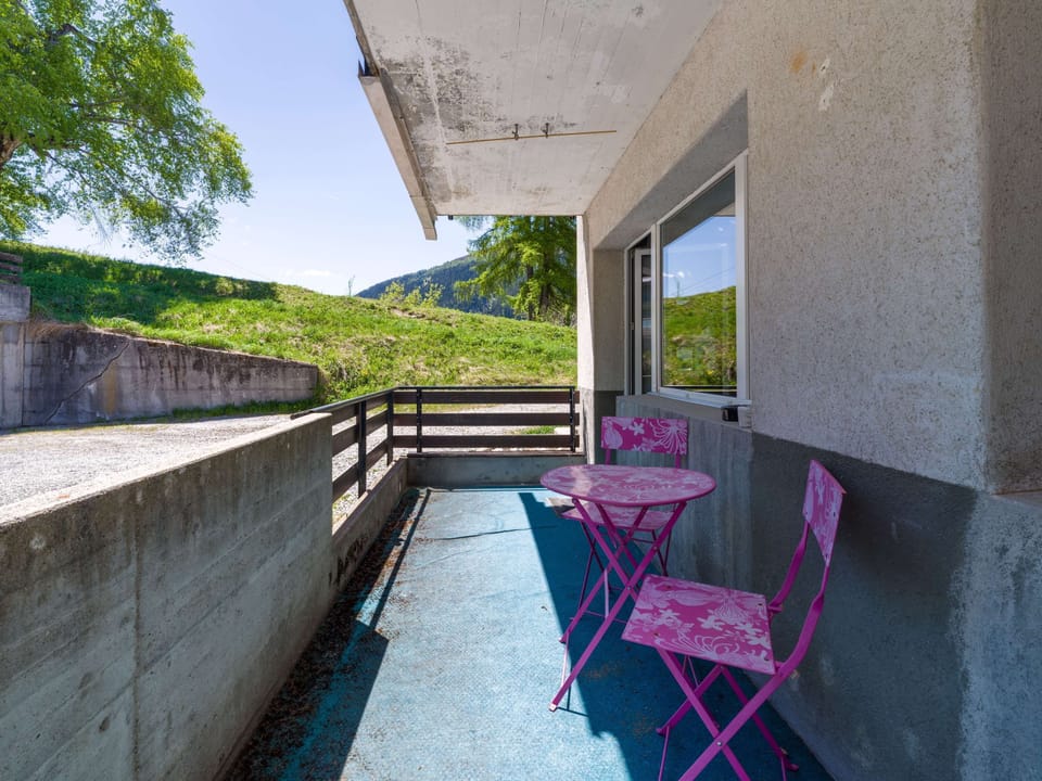 Balcony with small seating area and views toward the greenery
