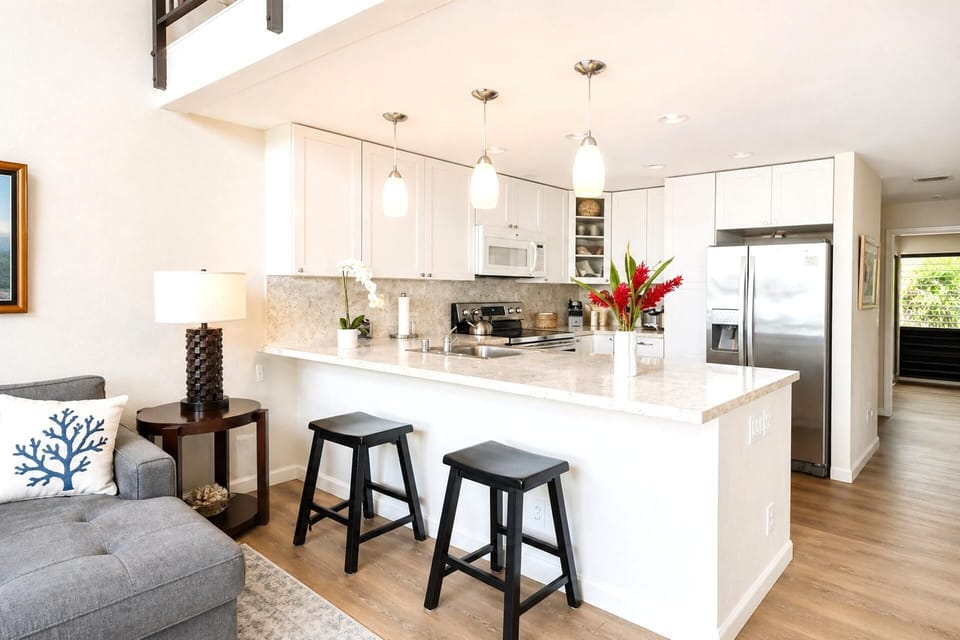 The kitchen features white cabinetry, bar seating, and plenty of counter space for cooking prep