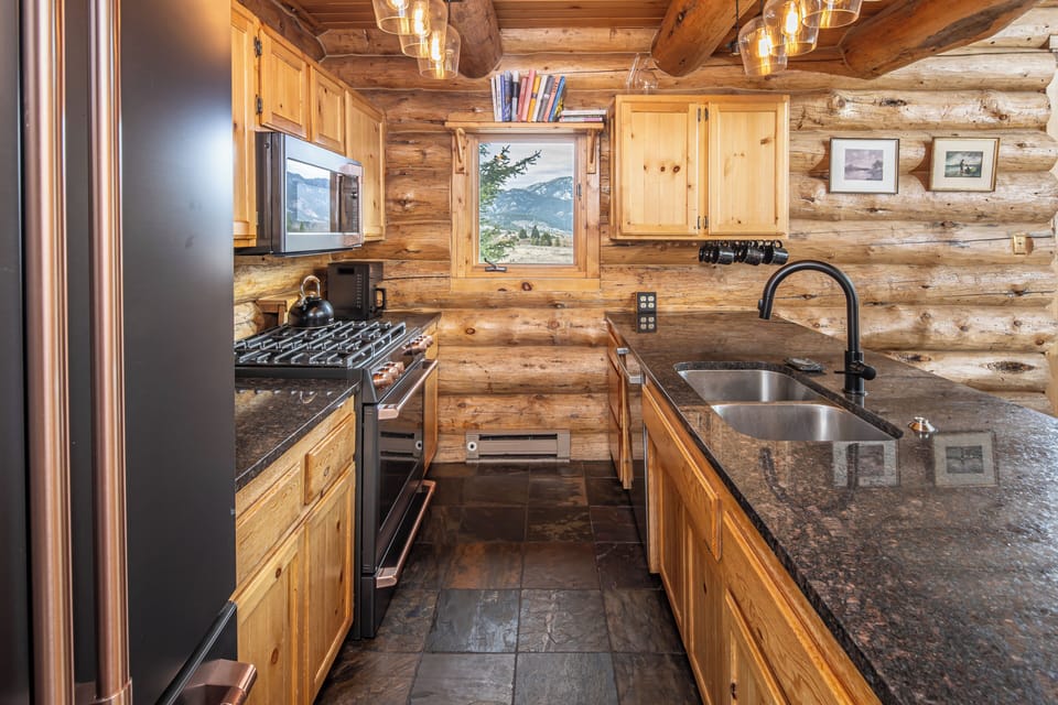 Your rustic log cabin kitchen blends mountain charm with modern convenience, featuring granite counters and scenic window views.