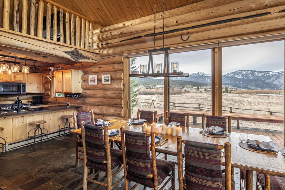Your rustic dining room overlooks breathtaking mountain vistas through floor-to-ceiling windows, where handcrafted log walls create the perfect backdrop for memorable meals.
