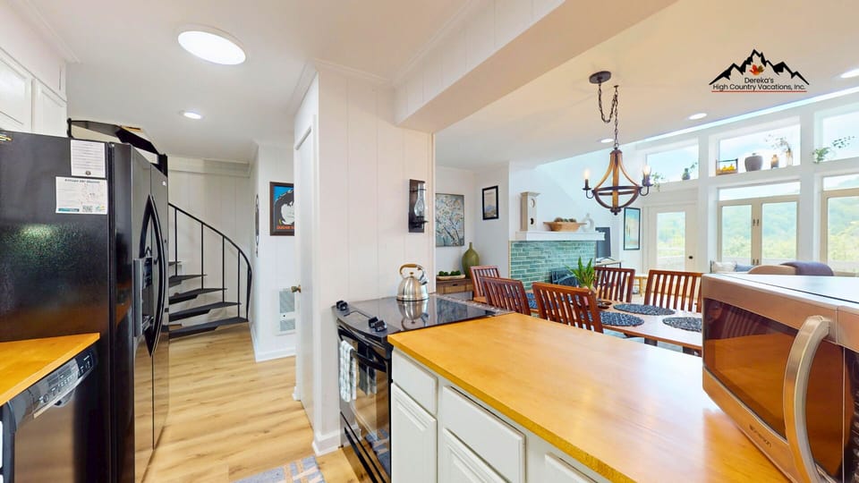 A sunlit open-concept kitchen and dining area invites you to gather and cook with mountain views through floor-to-ceiling windows, warm wood accents, and modern appliances at your fingertips.