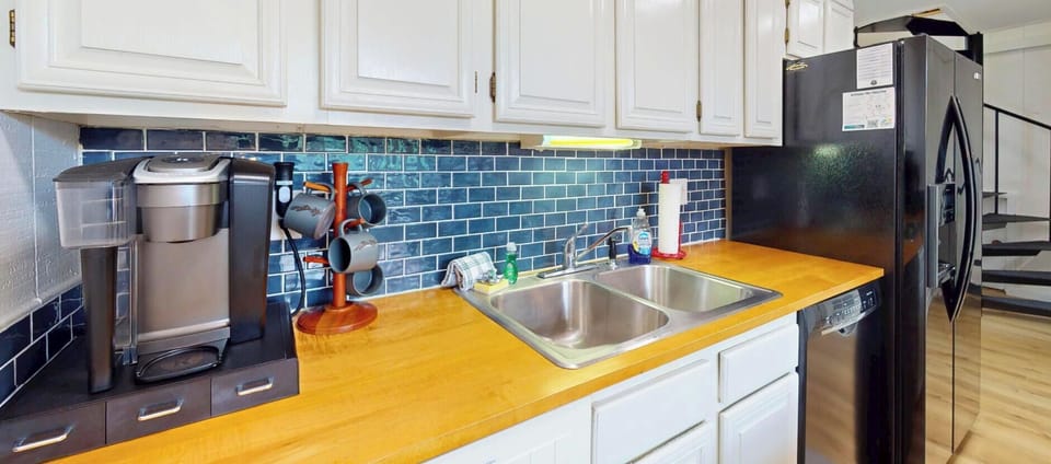 Your bright, fully equipped kitchen awaits with butcher block countertops and a striking blue subway tile backsplash. Enjoy stainless steel appliances and all the essentials you need to cook your favorite meals.
