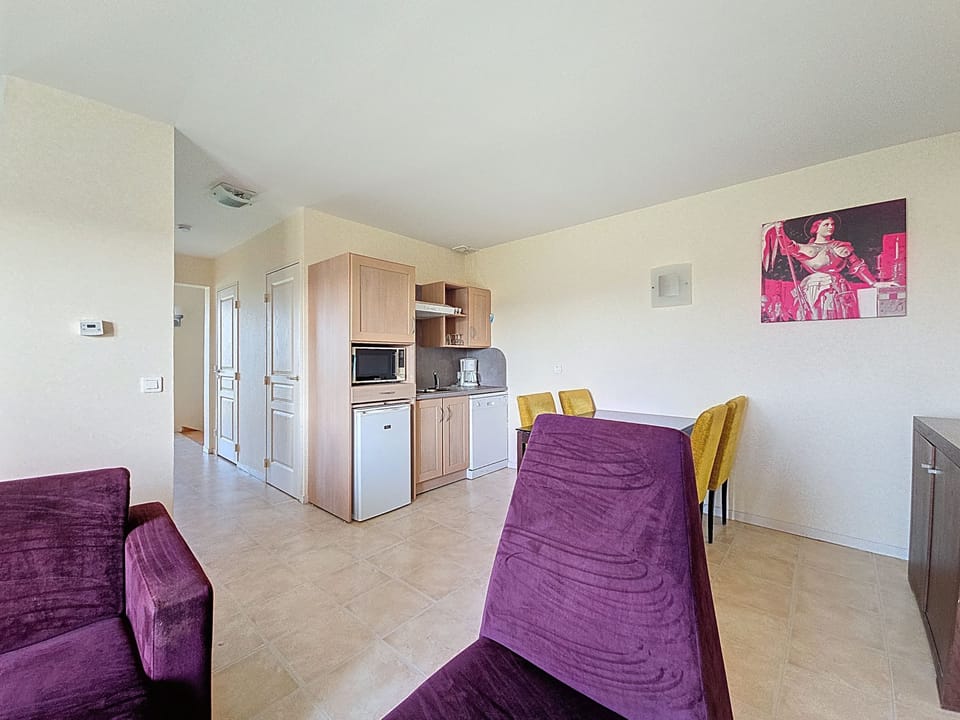 Open living area with purple and yellow seating, TV unit, and framed artwork on the walls