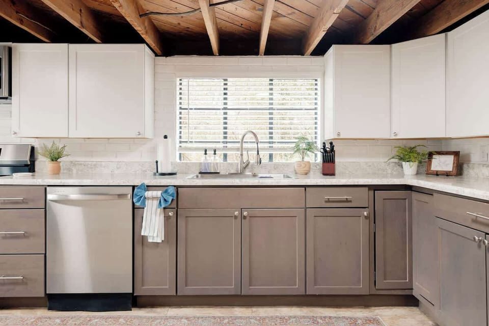 Bright, updated kitchen with stainless steel appliances, generous counter space, and modern cabinetry. Large windows bring in natural light, while exposed wood beams add character. Fully equipped and spacious—perfect for preparing meals.