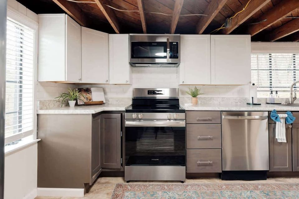 Bright, updated kitchen with stainless steel appliances, generous counter space, and modern cabinetry. Large windows bring in natural light, while exposed wood beams add character. Fully equipped and spacious—perfect for preparing meals.