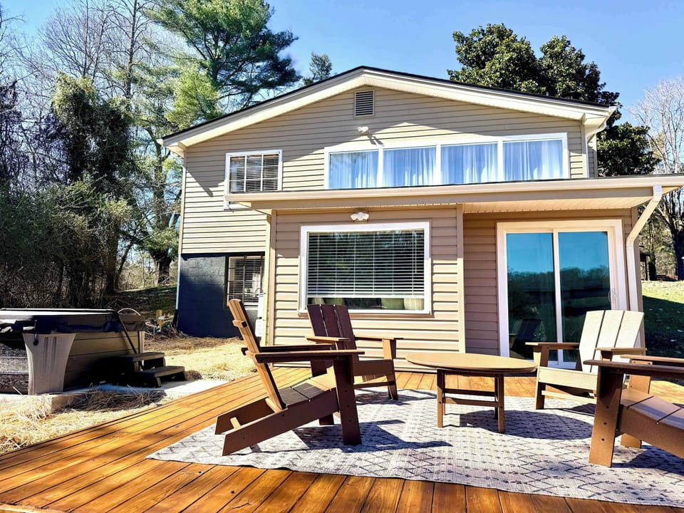 Spacious deck overlooking the backyard with views of Fort Patrick Henry Lake and the bridge in the distance. A great outdoor space for gathering, enjoying the fresh air, and stepping over to the hot tub just outside the primary suite.