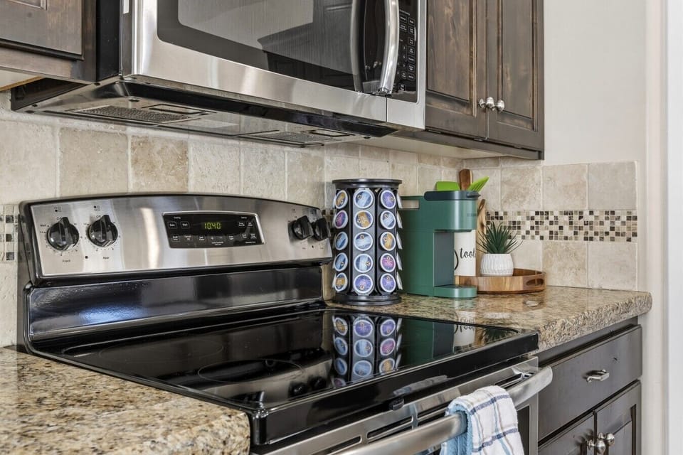 Kitchen stove with microwave, granite counters, and coffee station