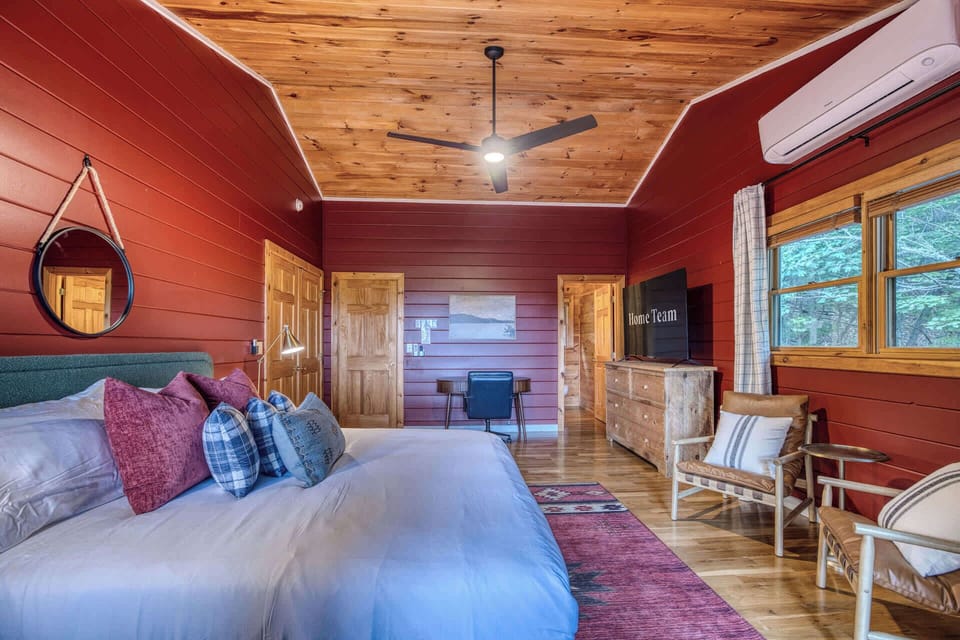 The perfect blend of cabin charm and modern comfort. This spacious king bedroom features eye-catching red wood walls, a ceiling fan, and mini-split AC to keep you perfectly comfortable, plus plenty of space to relax or catch up on remote work.