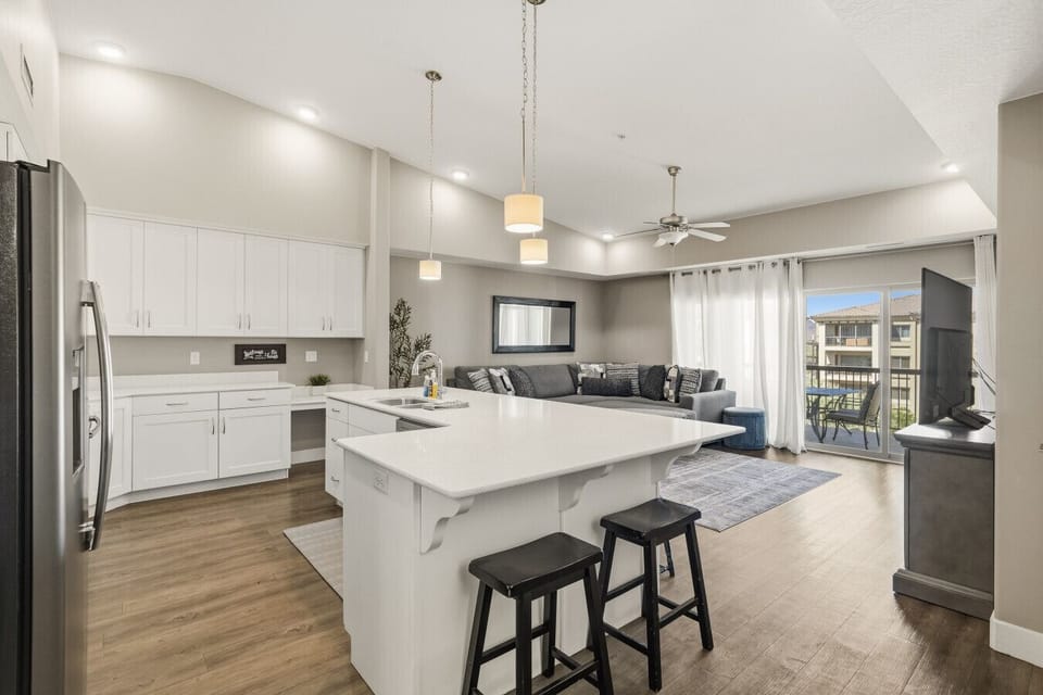 Open kitchen with island seating, living area, and balcony access.