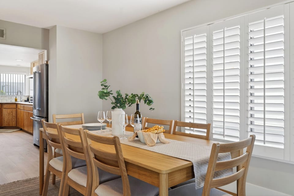 Open dining and lounge area with a stone fireplace, ocean-view balcony access, and relaxed coastal style.