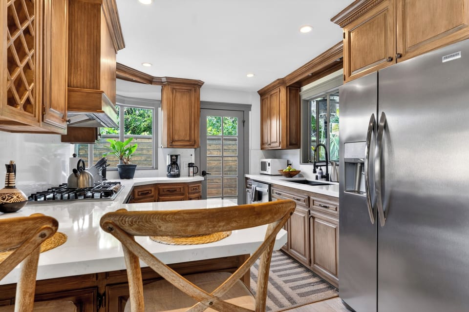 Premium details include a professional-grade gas range, a matching custom wood range hood, and a clean, bright tile backsplash.