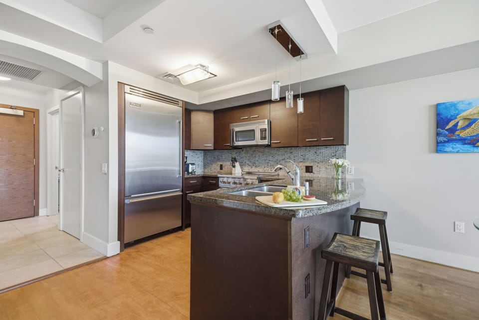 Gourmet kitchen equipped with premium stainless steel appliances, dark wood cabinetry, and an island breakfast bar.