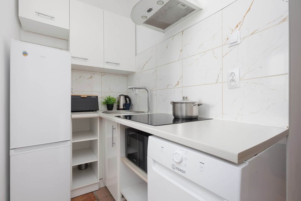 Modern white kitchen with compact appliances and clean design.