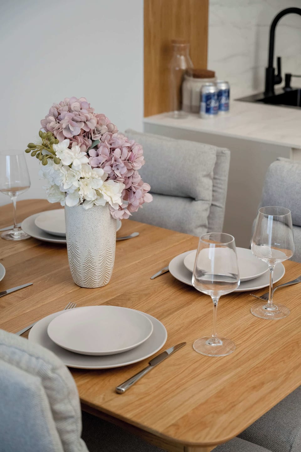 A dining table decorated with flowers and tableware creates a stylish place for meals. The bright interior gives the space a modern look.