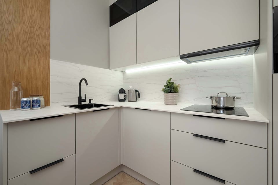 A sleek kitchenette corner with built-in appliances and soft lighting creates a modern and elegant atmosphere. Minimalist design and bright colors make the space feel spacious.