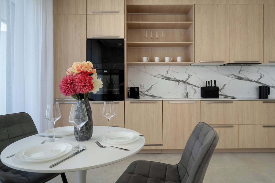 A dining table set within a stylish kitchen area, featuring decorative flowers as a centerpiece. The warm wood tones create a welcoming and homey atmosphere.