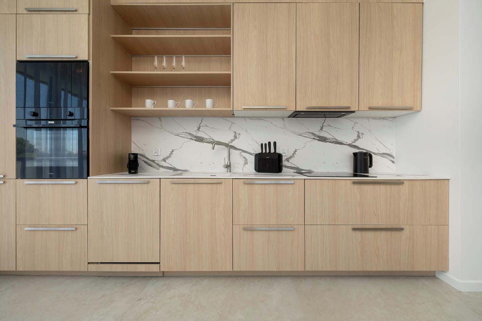 A modern kitchen with built-in wooden cabinetry and a clean, streamlined design. The space is well-organized and equipped for convenient cooking.
