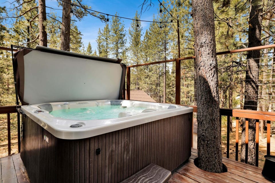 Cozy backyard with comfortable chairs, a BBQ grill, hot spa, and relaxing views of the surrounding pine trees and peaceful outdoor scenery.