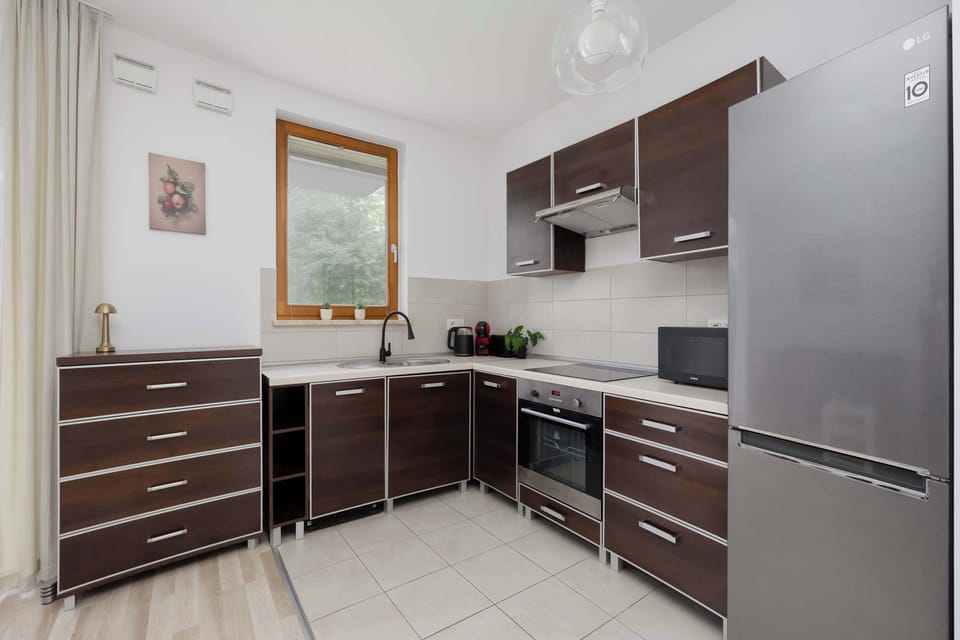 A sleek kitchen with dark brown cabinets, stainless steel appliances, and tiled flooring. The compact layout offers plenty of storage and workspace.