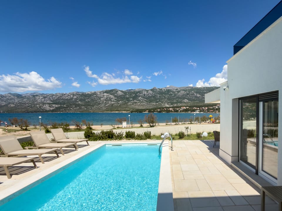 Heated pool at Villa Wave of Love with sun loungers and panoramic views of the sea and Velebit.