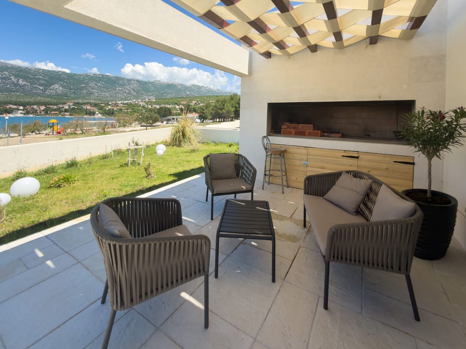 Covered terrace at Villa Wave of Love with lounge area, stone barbecue and beautiful views of the sea and Velebit.