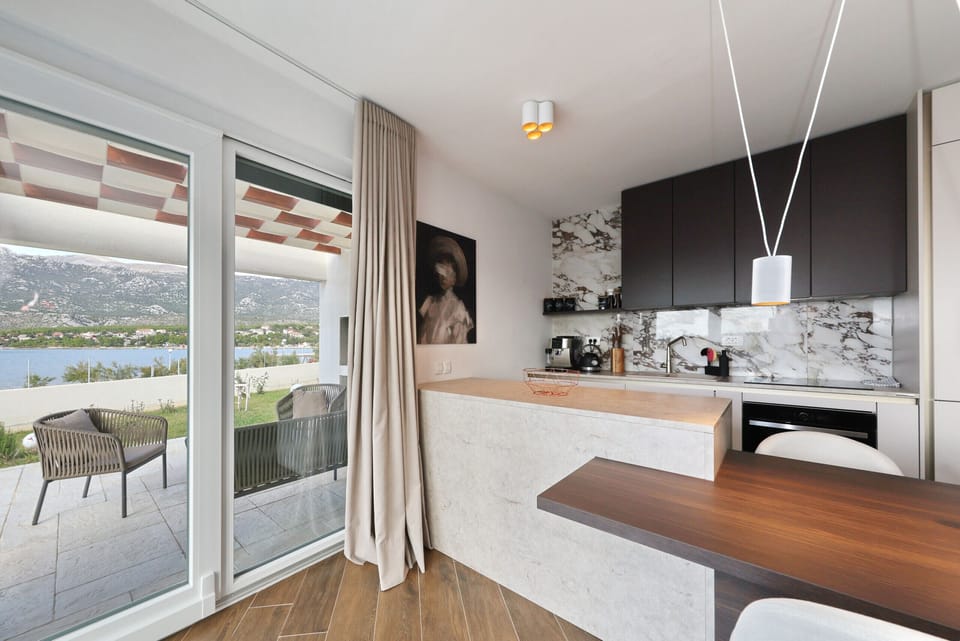 Modern open kitchen at Villa Wave of Love with dining area, terrace access and beautiful sea view.