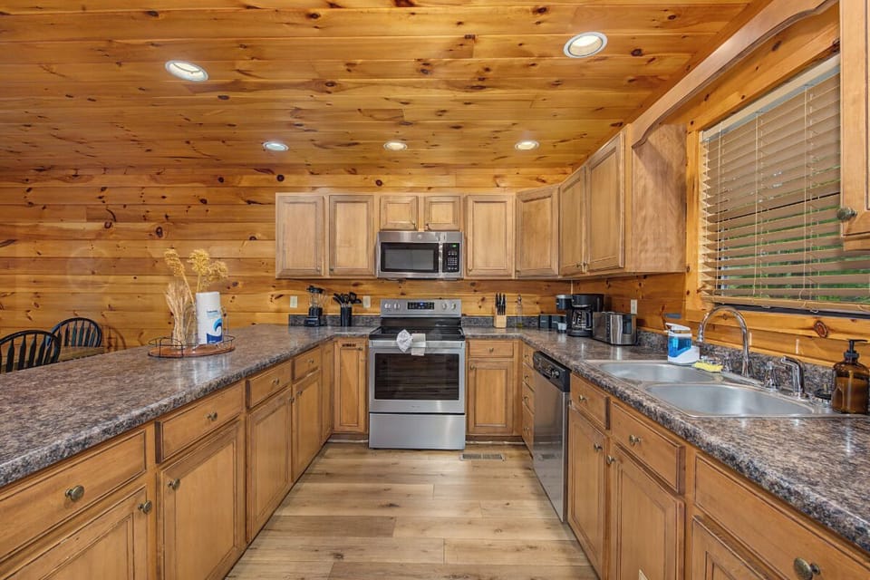 Your fully equipped kitchen features warm wood cabinetry, granite counters, and modern appliances—perfect for preparing meals together or brewing morning coffee while planning your next mountain adventure.