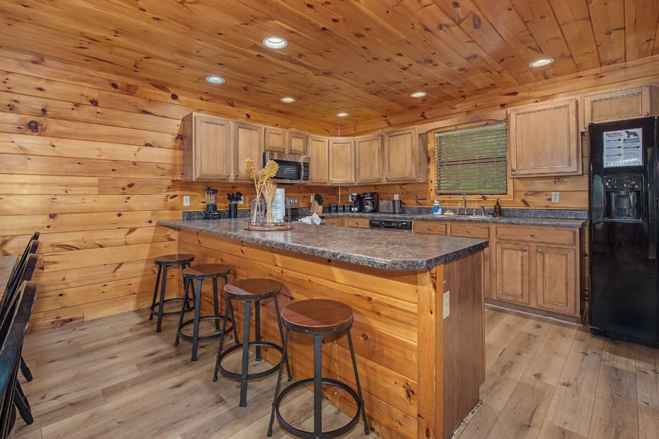Picture yourself preparing meals in this fully equipped kitchen, featuring warm wood finishes, granite countertops, modern appliances, and a welcoming breakfast bar where you can gather with loved ones over morning coffee.