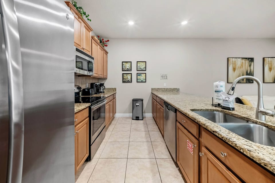 This bright, functional kitchen boasts sleek stainless steel appliances, warm wooden cabinetry, and a beautiful granite countertop, creating an inviting space perfect for gathering and preparing meals during your stay.