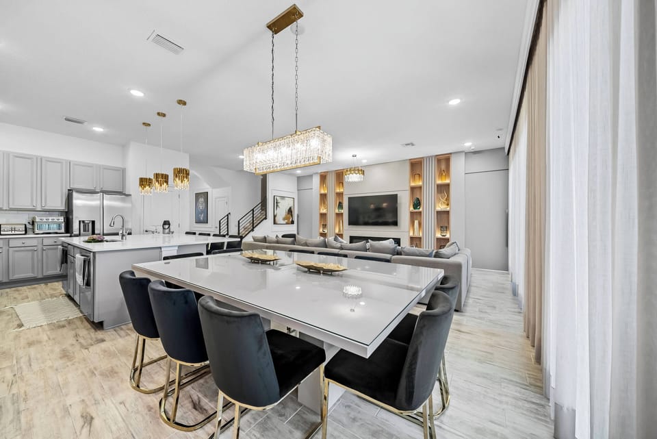 Enjoy a beautifully designed dining area featuring a sleek gray table and stylish black chairs that create a refined atmosphere. Golden accents and a shimmering light fixture add warmth, inviting you to relax and savor every meal.