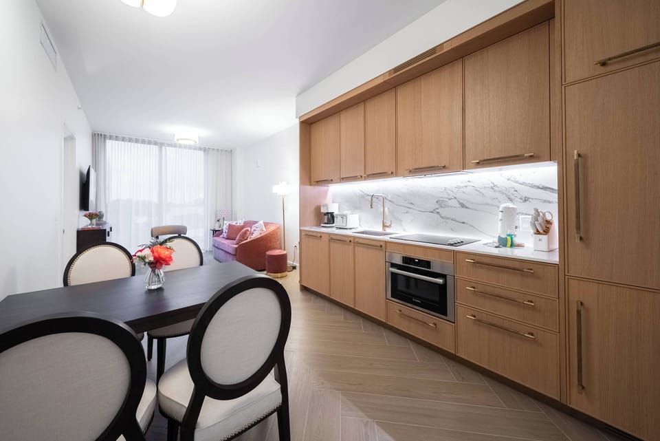 Enjoy culinary delights in a stylish kitchen with sleek cabinetry and elegant marble countertops. The inviting dining area, bathed in natural light, is perfect for meals or morning coffee, creating a warm and welcoming ambiance.