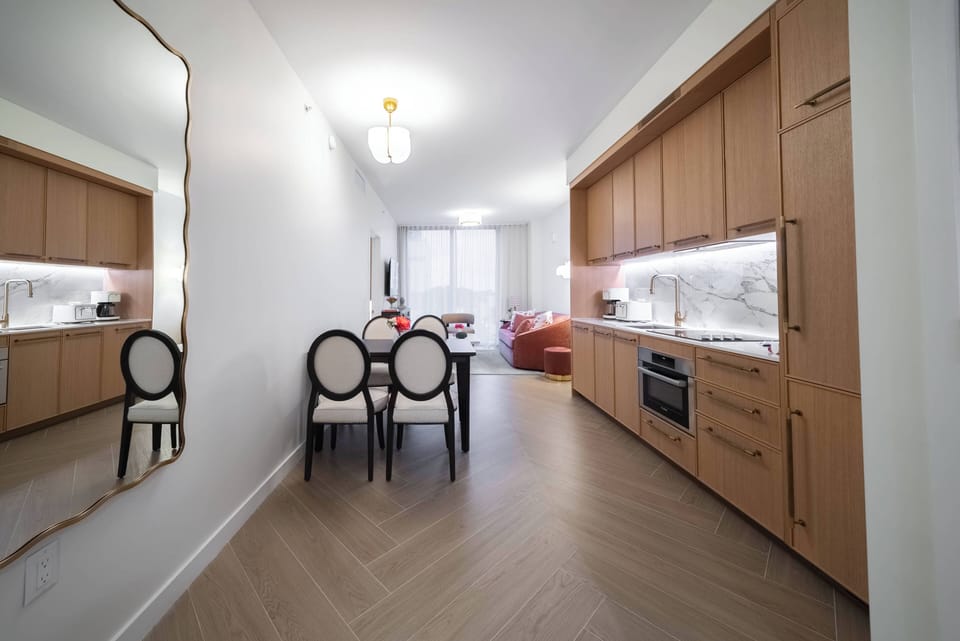 Discover a stylish kitchen featuring warm wood cabinetry and sleek marble surfaces, blending comfort and sophistication. The inviting dining area, illuminated by soft overhead lighting, is perfect for shared meals and laughter.