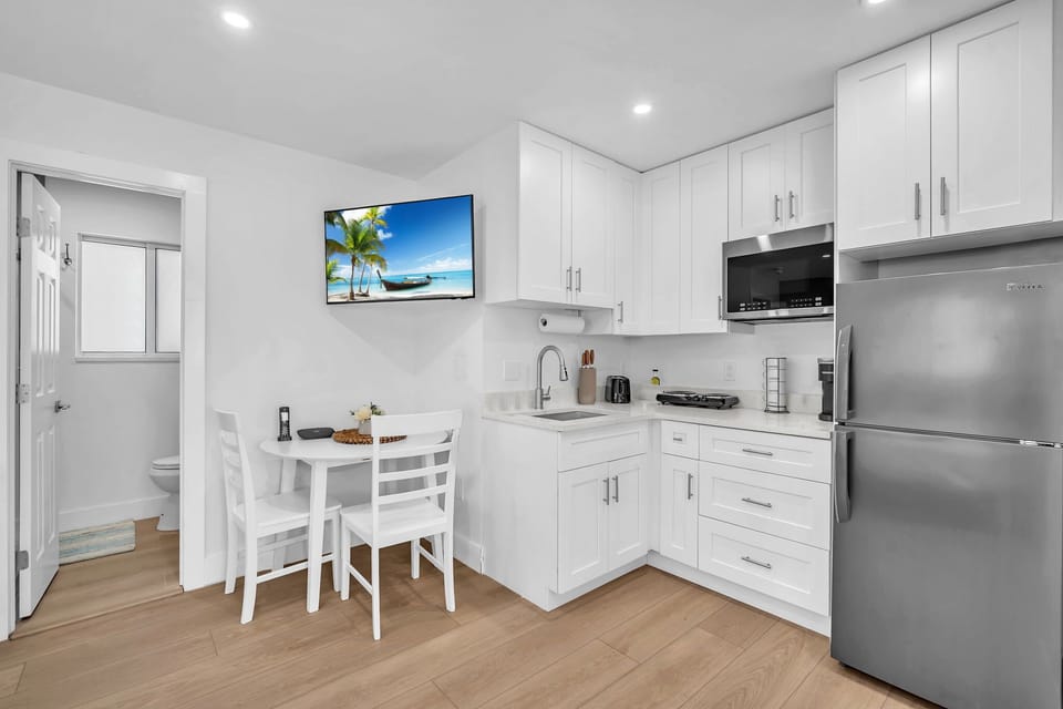 Clean and practical kitchenette featuring a fridge, electric cooktop, microwave, Keurig, and ample storage for your stay.