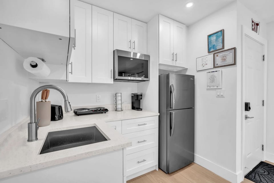 Clean and practical kitchenette featuring a fridge, electric cooktop, microwave, Keurig, and ample storage for your stay.