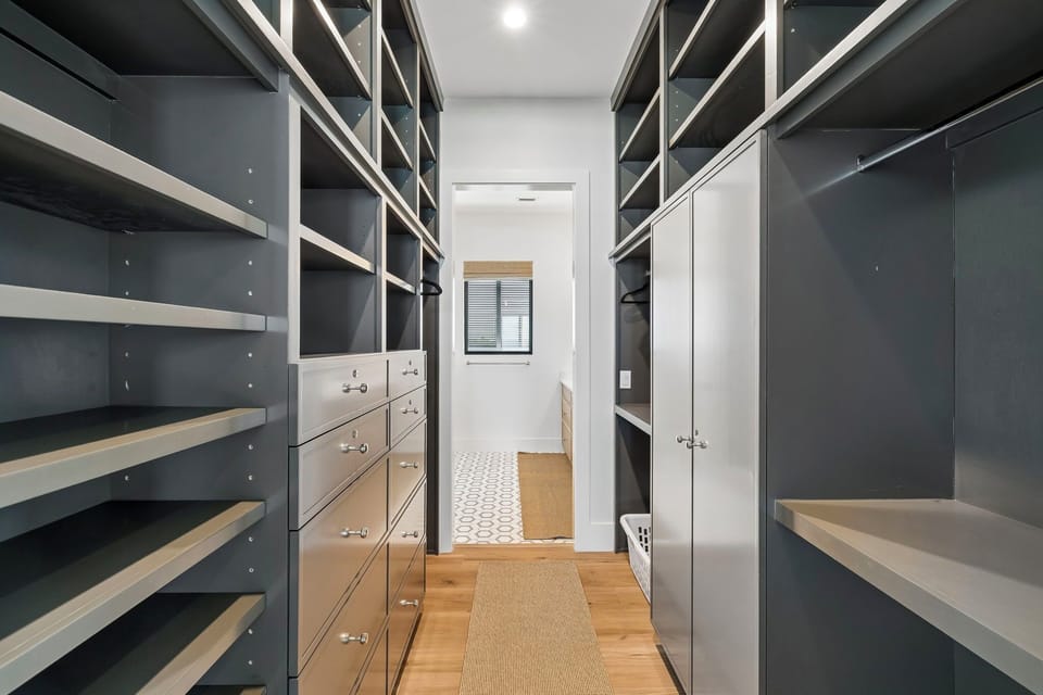 Store your wardrobe in this thoughtfully designed walk-in closet with custom shelving, hanging rods, and built-in drawers, providing generous storage and easy organization during your stay.