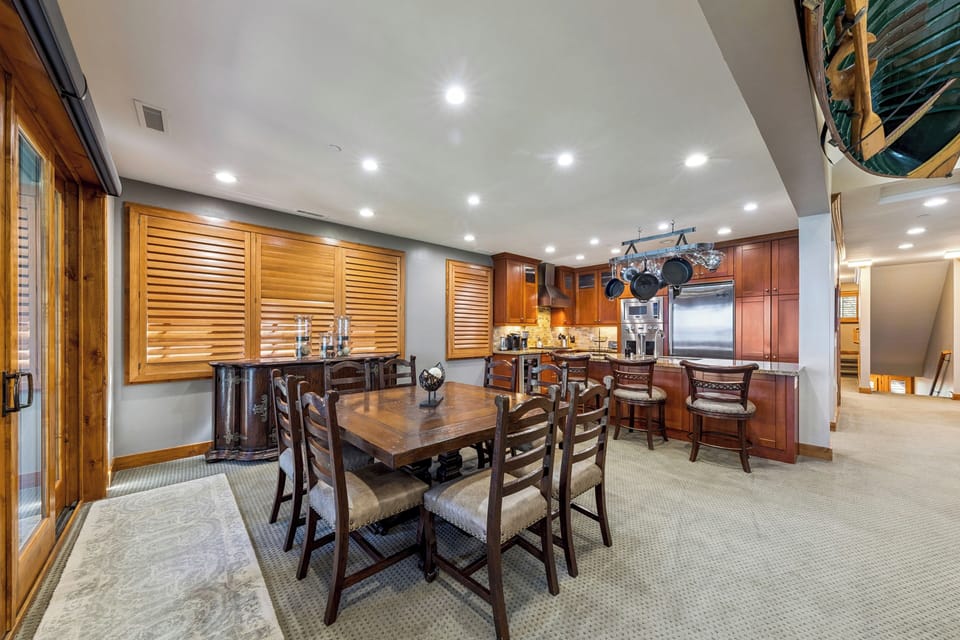 Gather around the rustic dining table where warm wood tones and thoughtful lighting set the scene for memorable meals together in your spacious, fully-equipped kitchen.