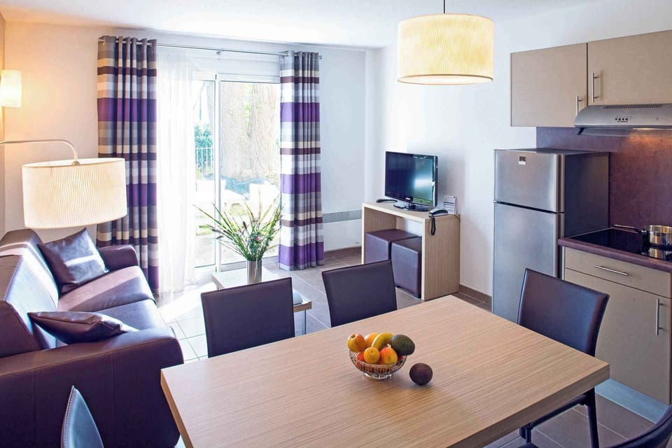 The living room's dark sofa and dining table seat four comfortably, with the parkland visible through the large windows.
