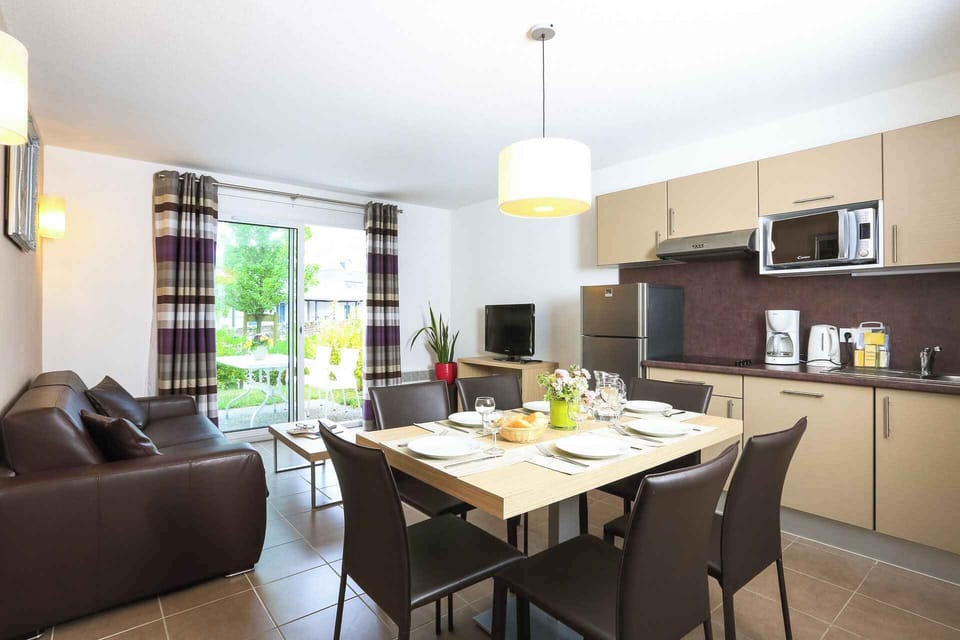 Kitchen and dining area on the ground floor, with white units, a 4-ring ceramic hob, dishwasher, and seating for six.