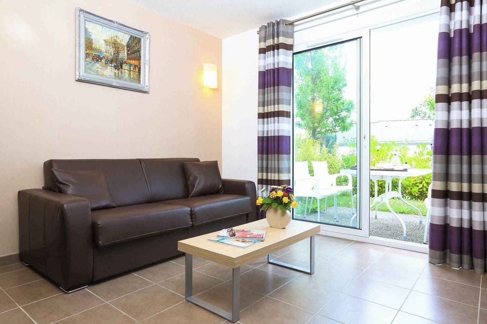Light-filled living area with warm furnishings and a bright colour palette — the sofa bed accommodates two extra guests.