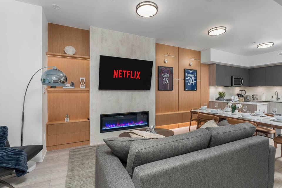 Open-concept living and dining area with Smart TV, fireplace, and modern kitchen.