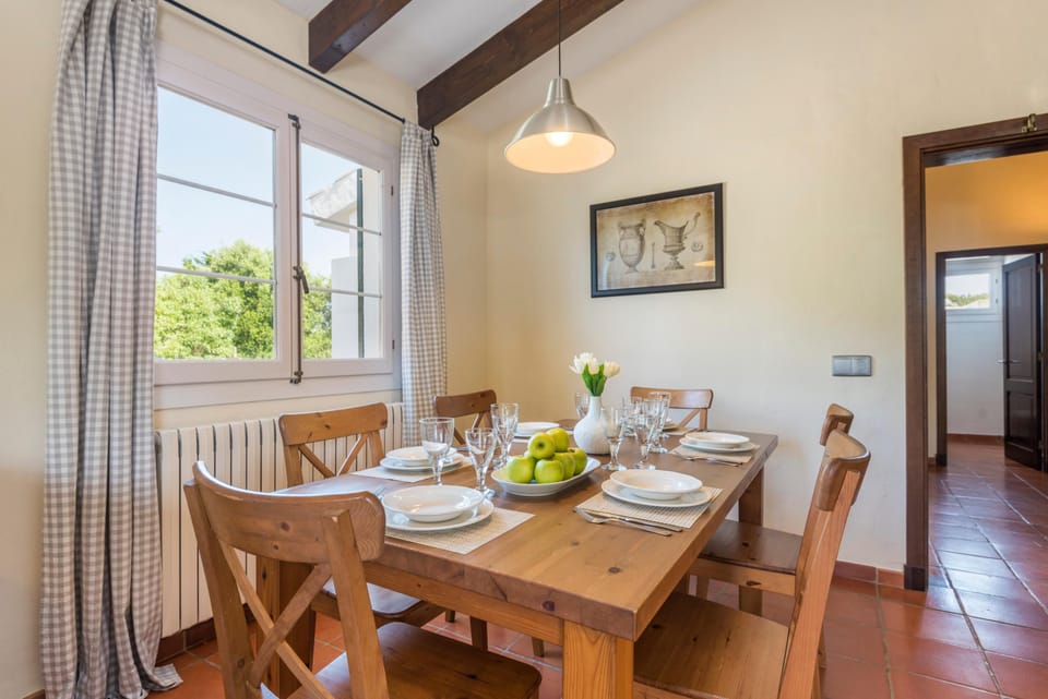 Zona de comedor en la cocina con mesa de madera rústica y luz natural directa