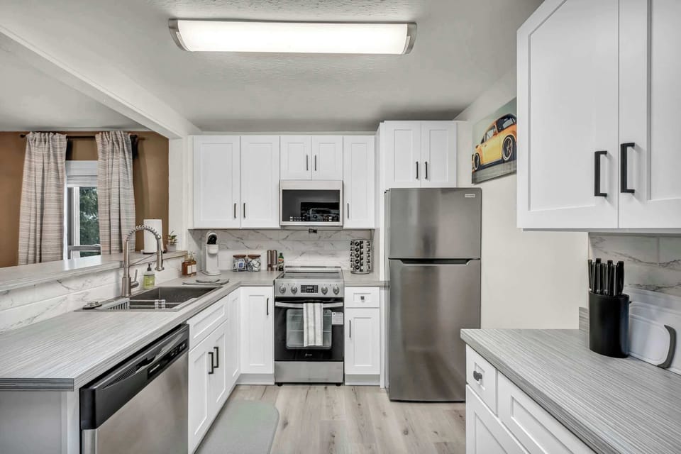 Sleek white kitchen w/ stainless steel appliances & plenty of counter space.

