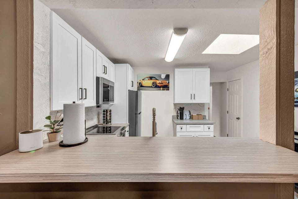 Spacious kitchen w/ white cabinetry & skylight bringing in natural light.
