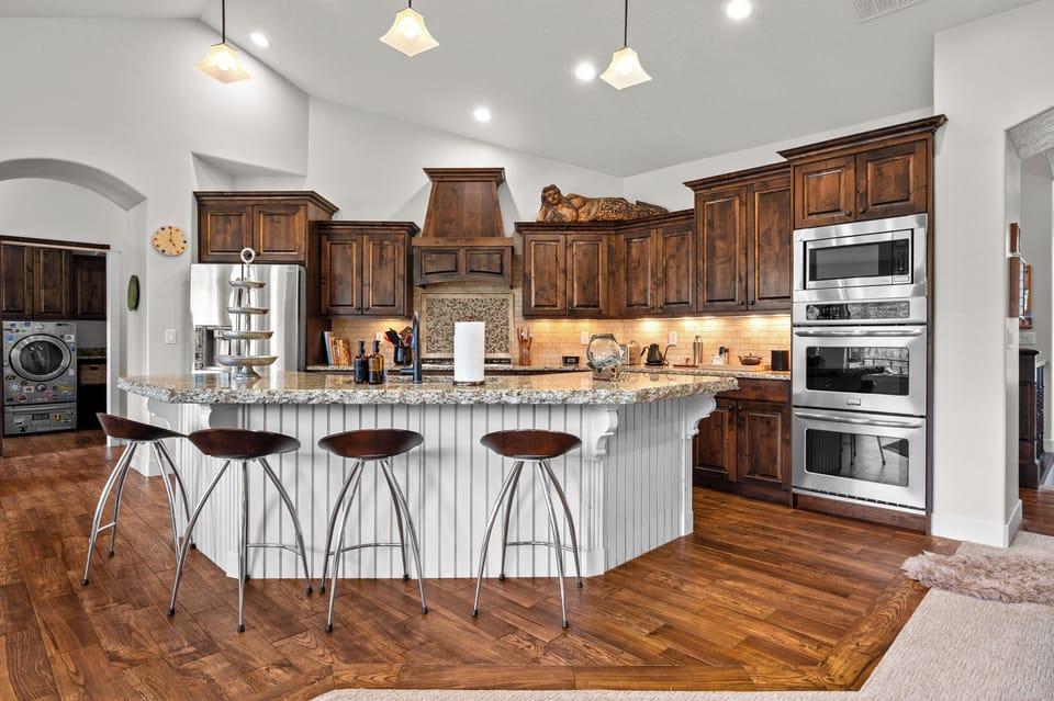 Chef's Kitchen with Seating for Four – Gather around the oversized granite island with bar seating, surrounded by premium appliances, abundant cabinetry, and plenty of space for preparing memorable family meals.