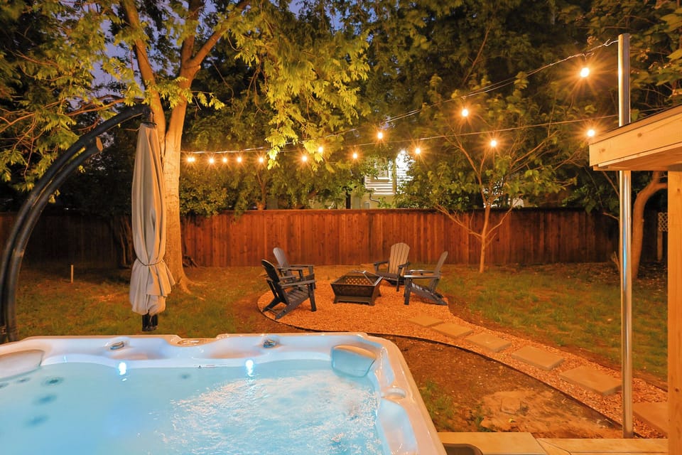 Dreamy backyard with large hot tub, fire pit, bistro lights and patio