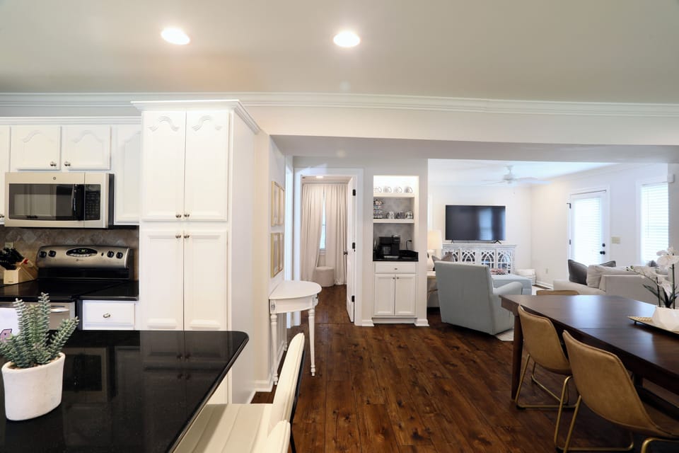 Bright open-concept kitchen, dining, and living area with warm wood floors