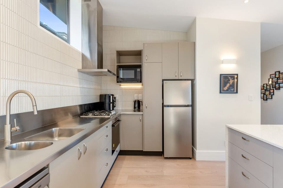 The kitchen - stainless benchtop, gas cooktop, and full-size fridge