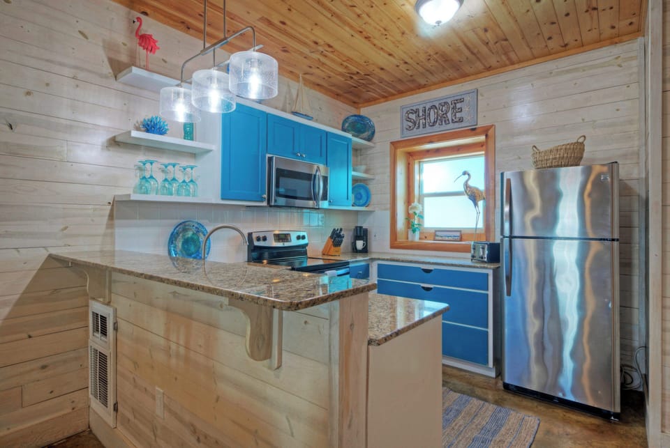 Bright, beachy kitchen with coastal-blue accents, stainless appliances, and easy flow into the dining and living spaces.